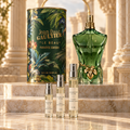Jean Paul Gaultier Le Beau Paradise Garden bottle and cylindrical packaging with Alabaster Elixir 2 ml, 5 ml and 10 ml decant atomizers on a marble display.