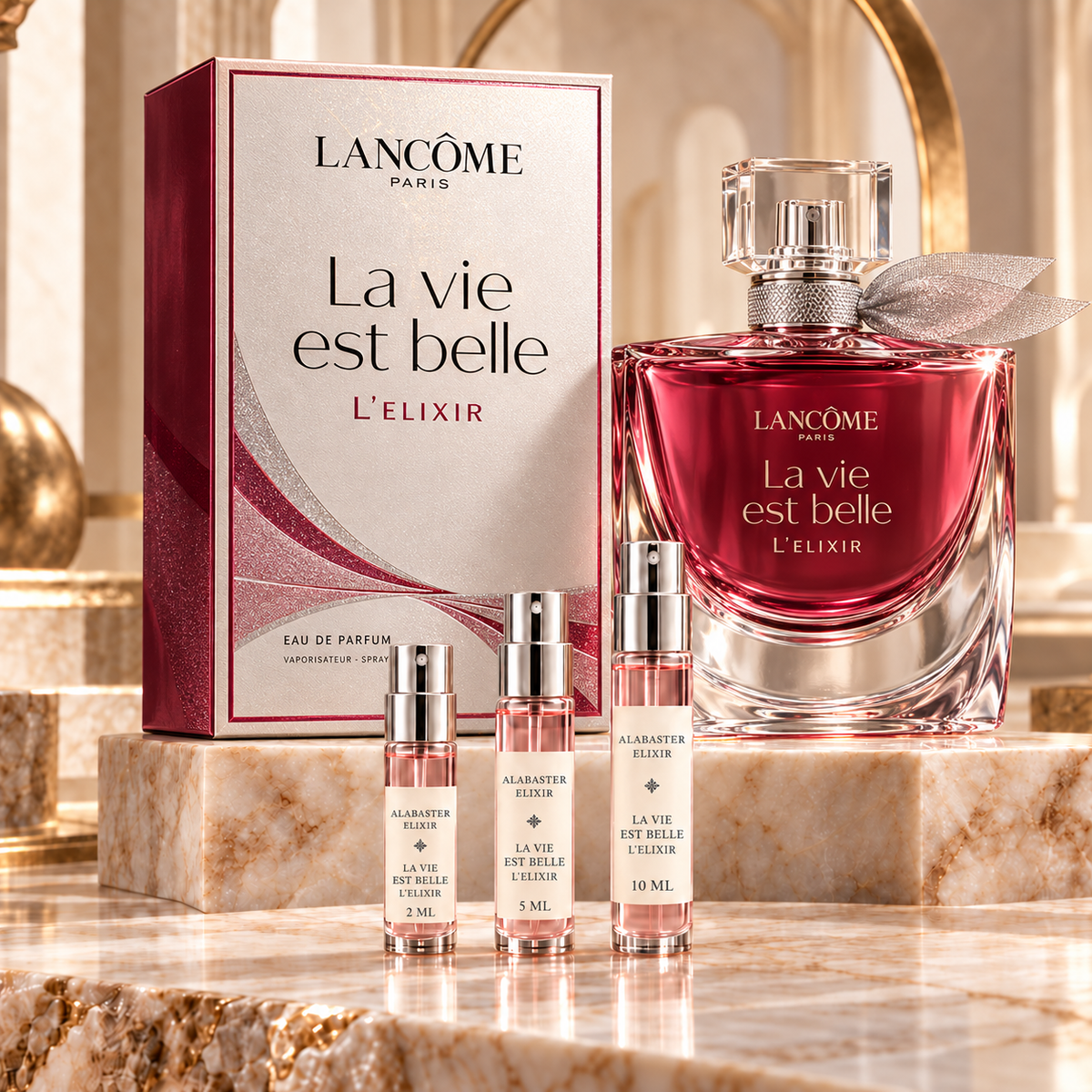Lancôme La Vie Est Belle L’Elixir bottle and box with Alabaster Elixir 2 ml, 5 ml and 10 ml decant atomizers on a marble display.